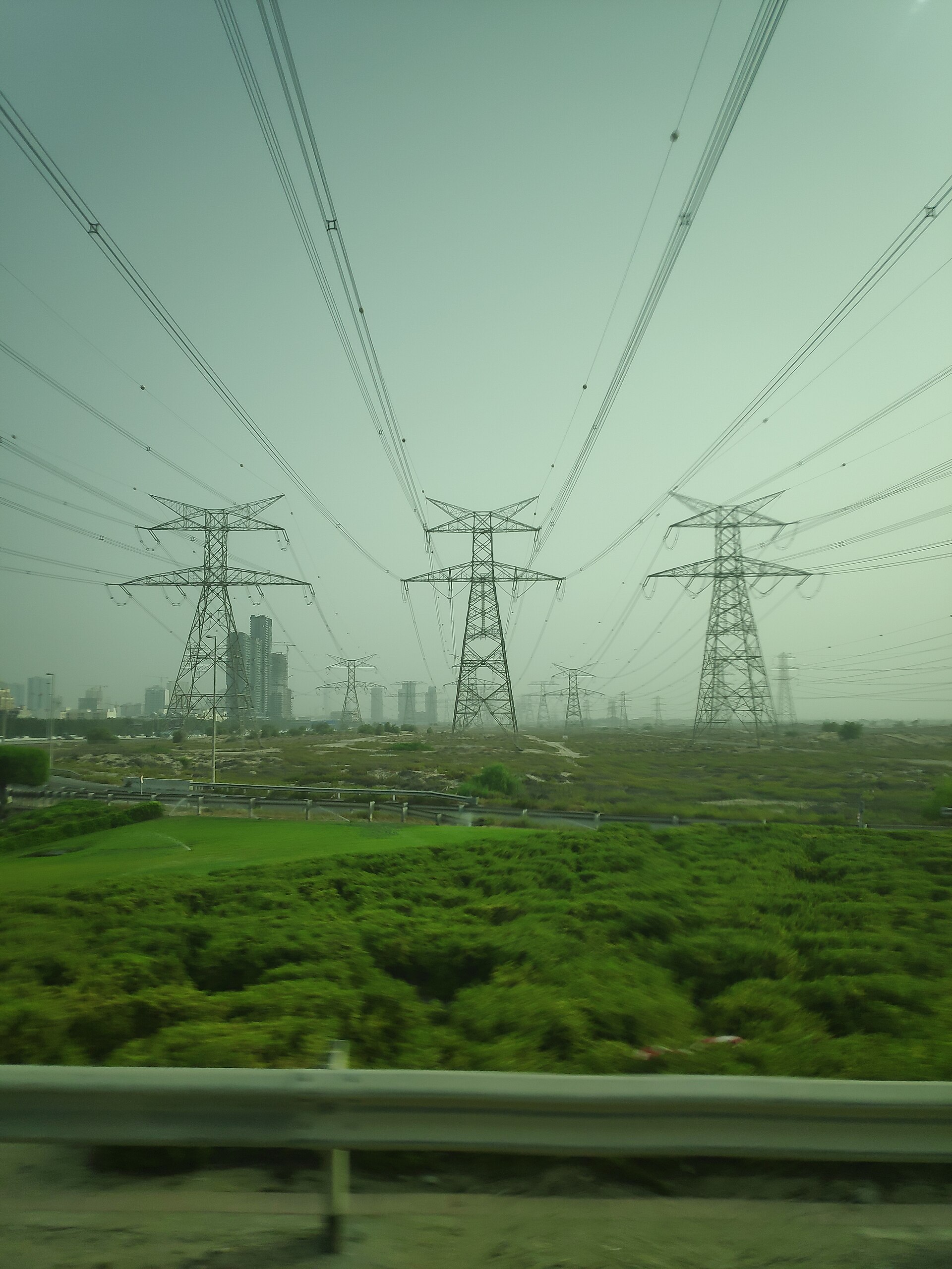 Power lines crossing a landscape under a bright sky