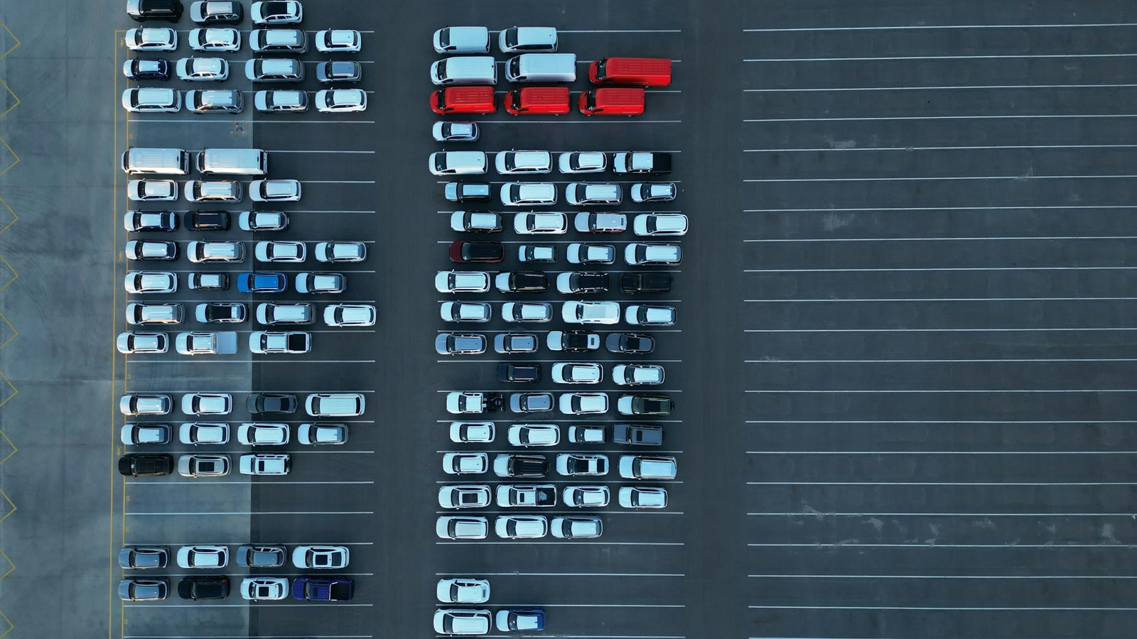 Rows of cars and pickup trucks seen from above in a large parking lot, showing the fleet mix behind fuel-economy rules.
